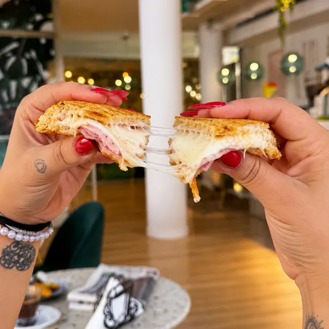 Dos manos abren un bikini de focaccia y el queso fundido se estira.