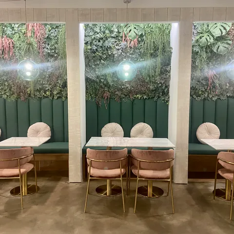 La sala de FORNO: banquetas capitoné verdes bajo un jardín vertical, mesas de mármol y sillas de terciopelo rosa.